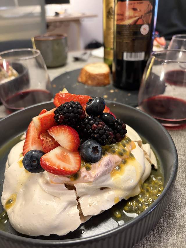 A pavlova topped with raspberry cream, strawberries,
                blackberries, blueberries and passion fruit.
